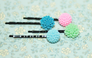 four hairpins with two blue, a green and a pink flower