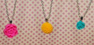 bright pink flower pendant necklace, bright yellow pendant necklace, and small blue rose necklace