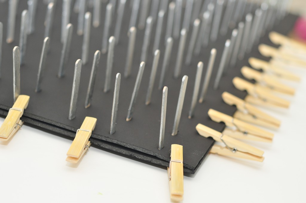 two sheets of foam board, silver wooden sticks poking out of the top and clothespins securing the sides.